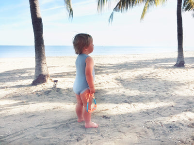 baby wearing merino singlet bodysuit by the beach