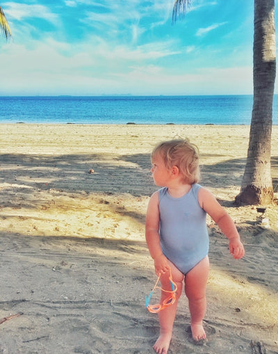 baby wearing merino singlet bodysuit by the beach
